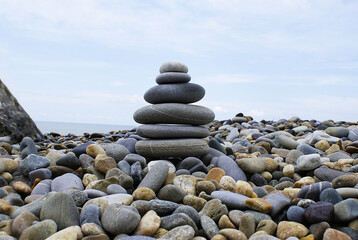 Fototapeta na wymiar Pyramid of round stones on the seashore, the concept of harmony, balance and meditation.