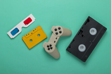 Anaglyph disposable paper 3d glasses, gamepad, video and audio cassette on mint green background. Retro media, entertainment 80s. Top view. Flat lay