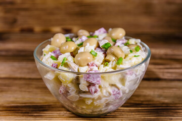 Salad with marinated mushrooms, sausage, onion, boiled potato and mayonnaise on a wooden table