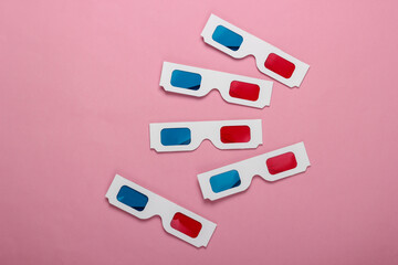 Many Stereoscopic anaglyph disposable paper 3d glasses on pink pastel background. Top view