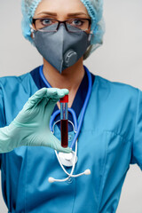 medical doctor nurse woman wearing protective mask and gloves - holding virus blood test tube