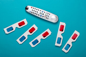 Many Anaglyph disposable paper 3d glasses and tv remote on  blue background. Tv time. Top view