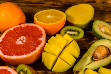 Still life with exotic fruits. Bananas, mango, oranges, avocado, grapefruit and kiwi fruits on wooden table