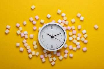 white clock with marshmallows on a yellow background. Top view. Pop art, minimalism