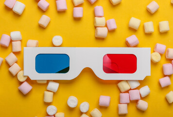 Anaglyph disposable paper 3d glasses with marshmallows on a yellow background. Top view. Pop art, minimalism