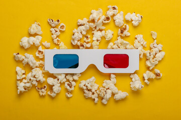 Movie time. Stereoscopic anaglyph disposable paper 3d glasses with popcorn on yellow background. Top view