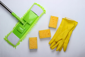 Cleaning products. Plastic green mop, gloves and sponges on white background. Disinfection and cleaning in the house. Top view