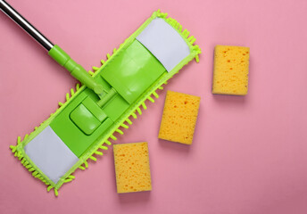 Cleaning products. Plastic green mop and sponges on pink background. Disinfection and cleaning in the house. Top view