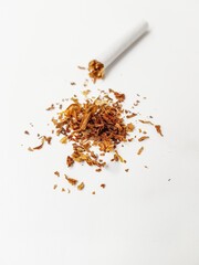 A broken cigarette and a pile of tobacco leaves on a white background.