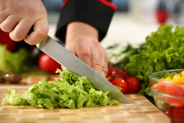 Professional cook cutting salad on the board