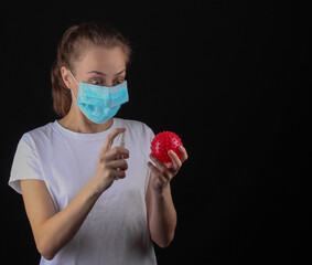Woman in a median face mask holding model strain virus and disinfects with antiseptic on a black...