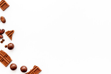 Chocolate background on white table top-down frame. Sweet desserts concept. Copy space
