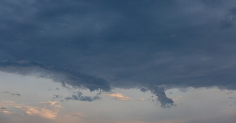 Beautiful dramatic gray and white clouds on blue sky, variety of shapes, silhouettes and shades at sunset time