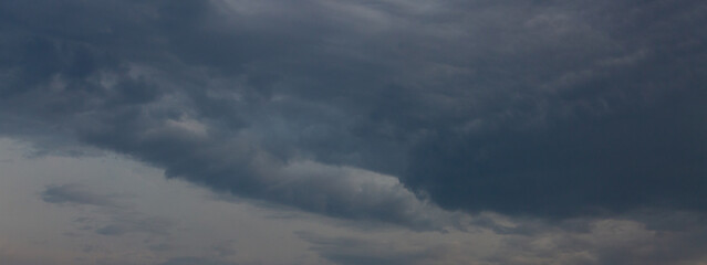 Beautiful dramatic gray and white clouds on blue sky, variety of shapes, silhouettes and shades at sunset time