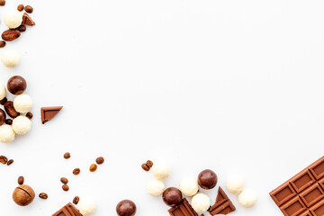 Candy background with chocolate on white table top view frame. Sweets desserts concept. Space for text