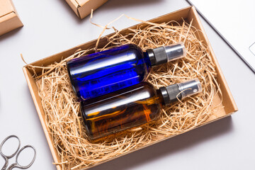 Set of brown and blue glass spray bottles packed in cardboard box on office desk