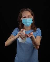 Woman disinfects hands with an antiseptic on a black background. Hygiene in covid-19 pandemic