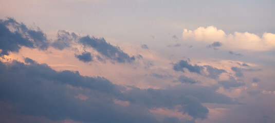 Beautiful dramatic gray and white clouds on blue sky, variety of shapes, silhouettes and shades at sunset time