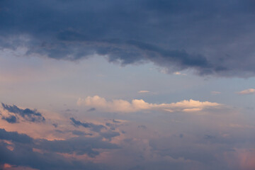 Fototapeta premium Beautiful dramatic gray and white clouds on blue sky, variety of shapes, silhouettes and shades at sunset time