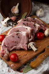 Meat, pork, steaks pork loin on a wooden background. Raw pork marinated meat isolated with vegetables. Advertising for meat shop and farm. Various kinds of meat and ready to cook concept. Top view.