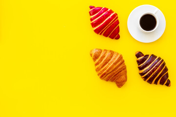 Coffee and croissants on yellow background top view