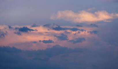 Beautiful dramatic gray and white clouds on blue sky, variety of shapes, silhouettes and shades at sunset time
