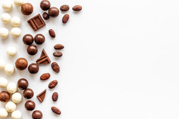 Sweets background with chocolate pralines on white desk top-down frame copy space