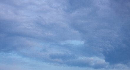Beautiful dramatic gray and white clouds on blue sky, variety of shapes, silhouettes and shades at sunset time
