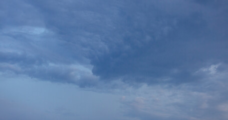 Beautiful dramatic gray and white clouds on blue sky, variety of shapes, silhouettes and shades at sunset time