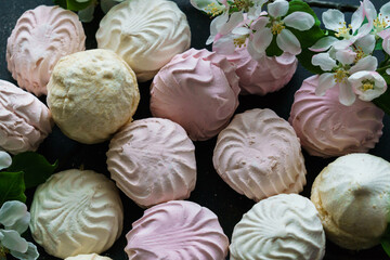 Delicious delicate white-pink marshmallows along with a flowering branch of an apple tree.