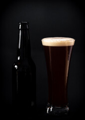 tasty craft beer in glass with bottle next to it and black background