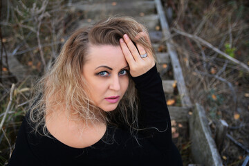 Beautiful girl looking at the camera. A thoughtful look. Portrait on the wooden stairs.
