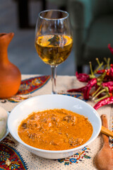 Georgian traditional food soup Kharcho or walnuts souse with beef meal, dry red pepper, tomatoes and other ingredients. Withe wine and wooden spoon.