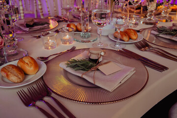 Close up shot of a luxury alfresco wedding reception table set up at the countryside; crystal tableware and burning candles.