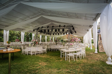 A luxury alfresco wedding reception set up at the countryside; white rustic tiffany chairs, top...