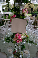 Table number stand of a luxury alfresco wedding reception at the countryside; white rustic tiffany chairs, top table flower arrangements and crystal center pieces