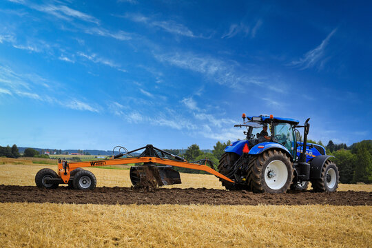Farmer Works With New Holland Tractor and Leveller.  Illustrative Editorial Content. 