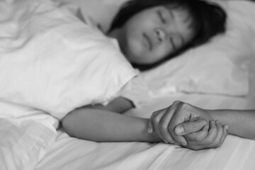 Child patient with IV line in hand sleep on hospital bed with mother's hand holding together to support ill daughter.Medical palliation healthcare concept