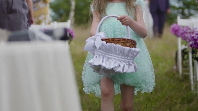 Slow motion of a wedding flower girl holding a basket. Little maid of honor