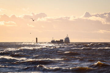 Obraz premium Late sunset view of old lighthouse pier and large storm waves.