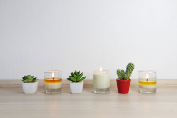 aromatic scented candles and small cactus in the pots are displayed on the wooden table in minimal zen design bedroom during Christmas party with family members