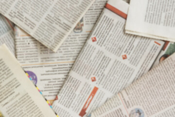 Lots of old newspapers on horizontal surface. Background texture, top view, blurred