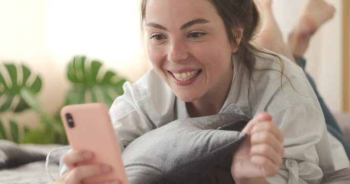 Astonished woman celebrating online success using mobile phone at home