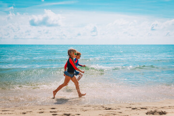 Fototapeta na wymiar happy girl and boy run play with waves on beach