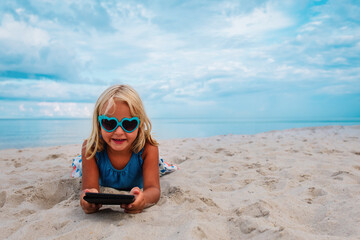 little girl reading e-book at sand beach, kid learning on vacation