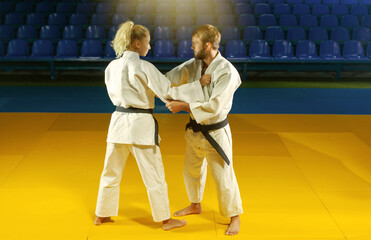 Martial arts. Sparing Portners. Sport man and woman in white kimono train judo captures in the...