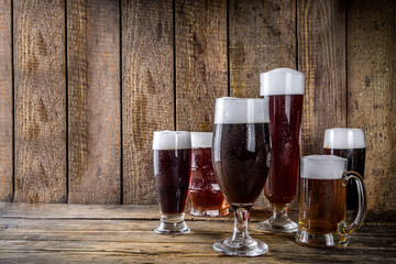 Different sorts of craft beer on wooden bar background. Set of various beer glasses and mugs. Beer tasting concept