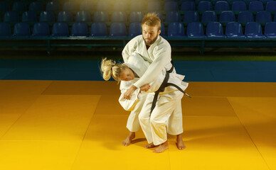Martial arts. Sparing Portners. Sport man and woman in white kimono train judo throws and captures...