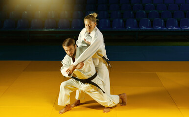 Martial arts. Sparing Portners. Sport man and woman in white kimono train judo throws and captures...