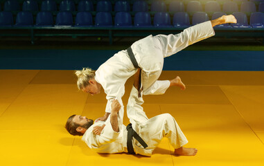 Martial arts. Sparing Portners. Sport man and woman in white kimono train judo throws and captures...